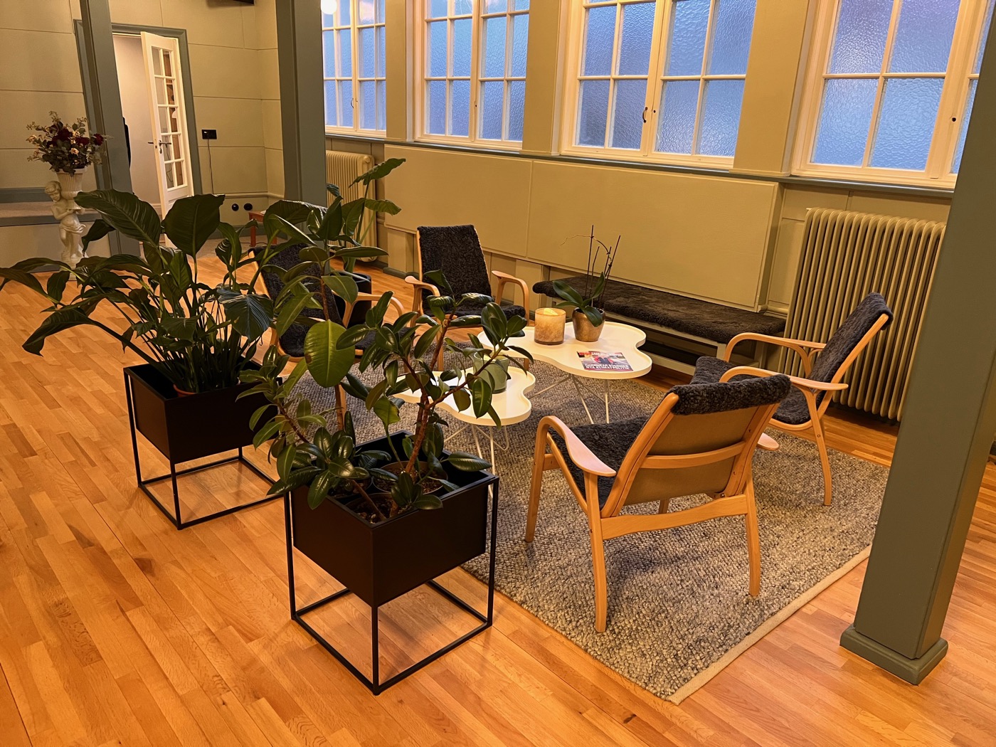 Mysig lounge med fåtöljer och växter vid bågfönstren