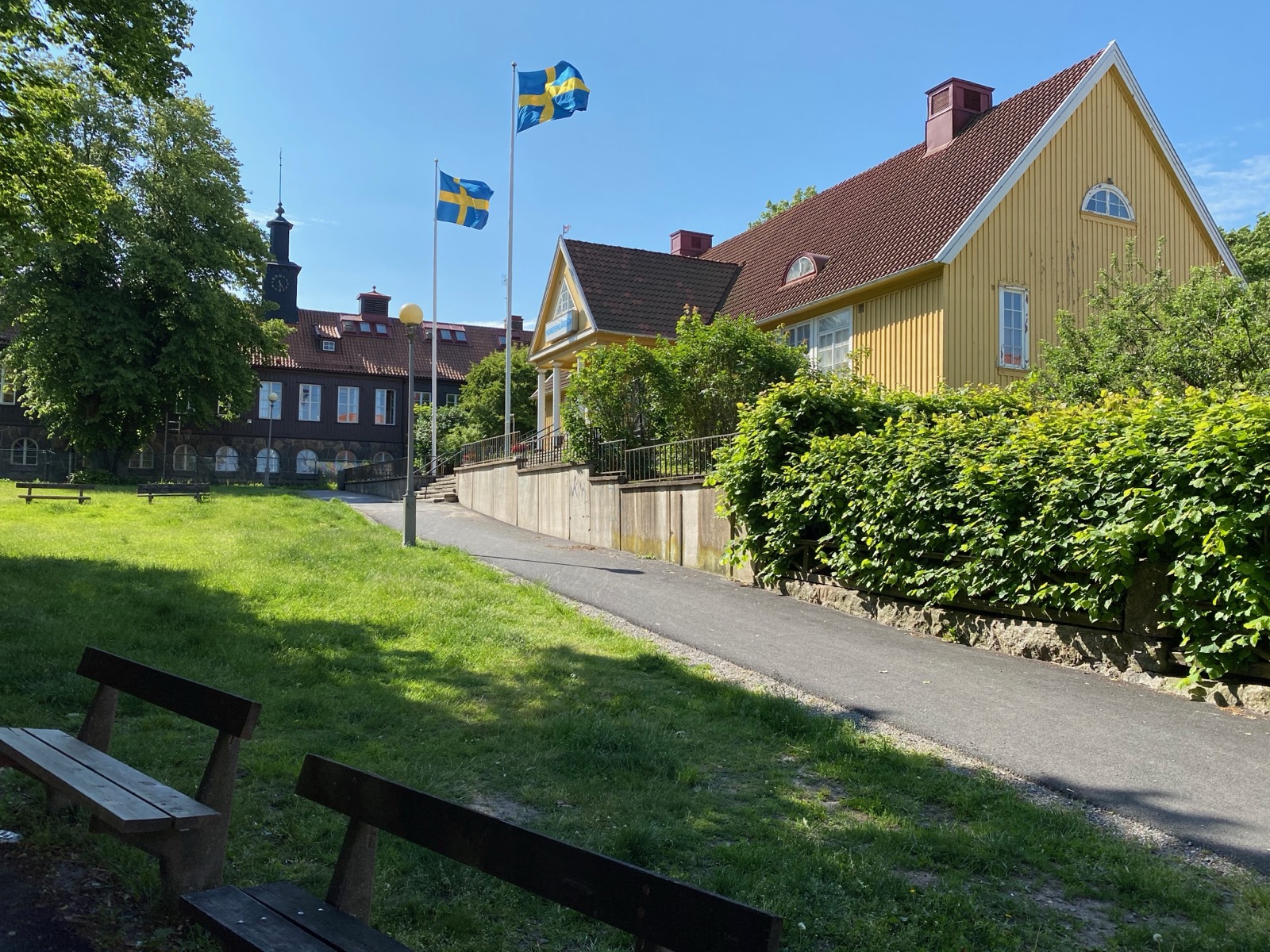 Villa Bagaregården sedd från parken, med flaggor och Bagaregårdsskolan bakom